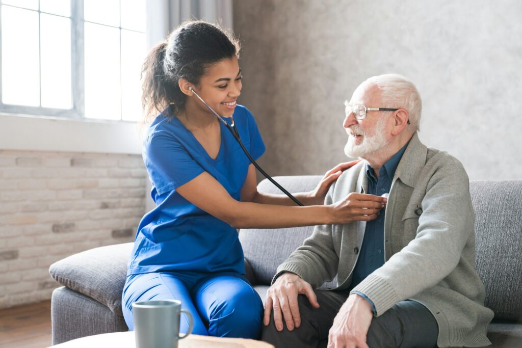 Female attending physician holding stethoscope listening old patient during homecare visit.