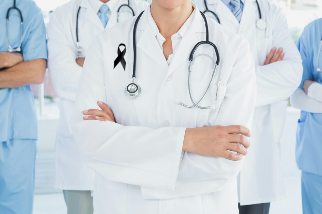 Mid section of team of doctors with black ribbon standing with their hands folded